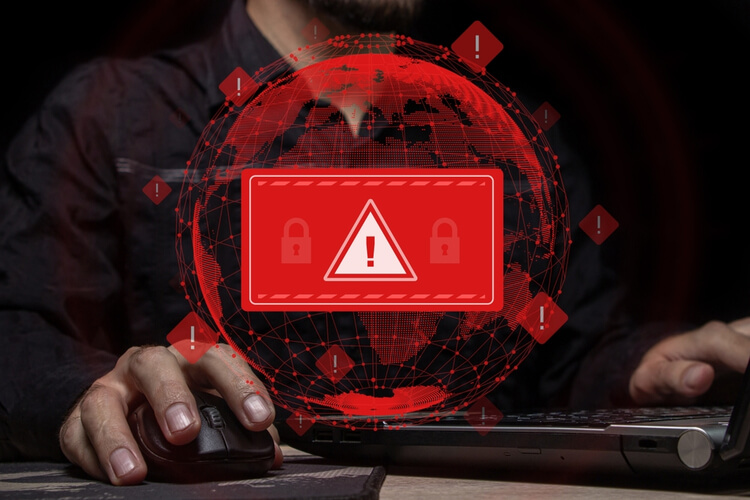 Pessoa utilizando computador com alerta de vazamento de dados em vermelho.