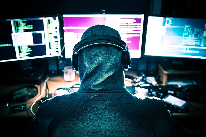 Membro de um dos grupos de hackers utilizando o computador com várias telas, para efetuar ataque.