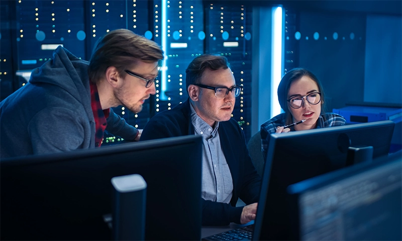 Foto de uma equipe de cibersegurança conversando em frente ao computador.